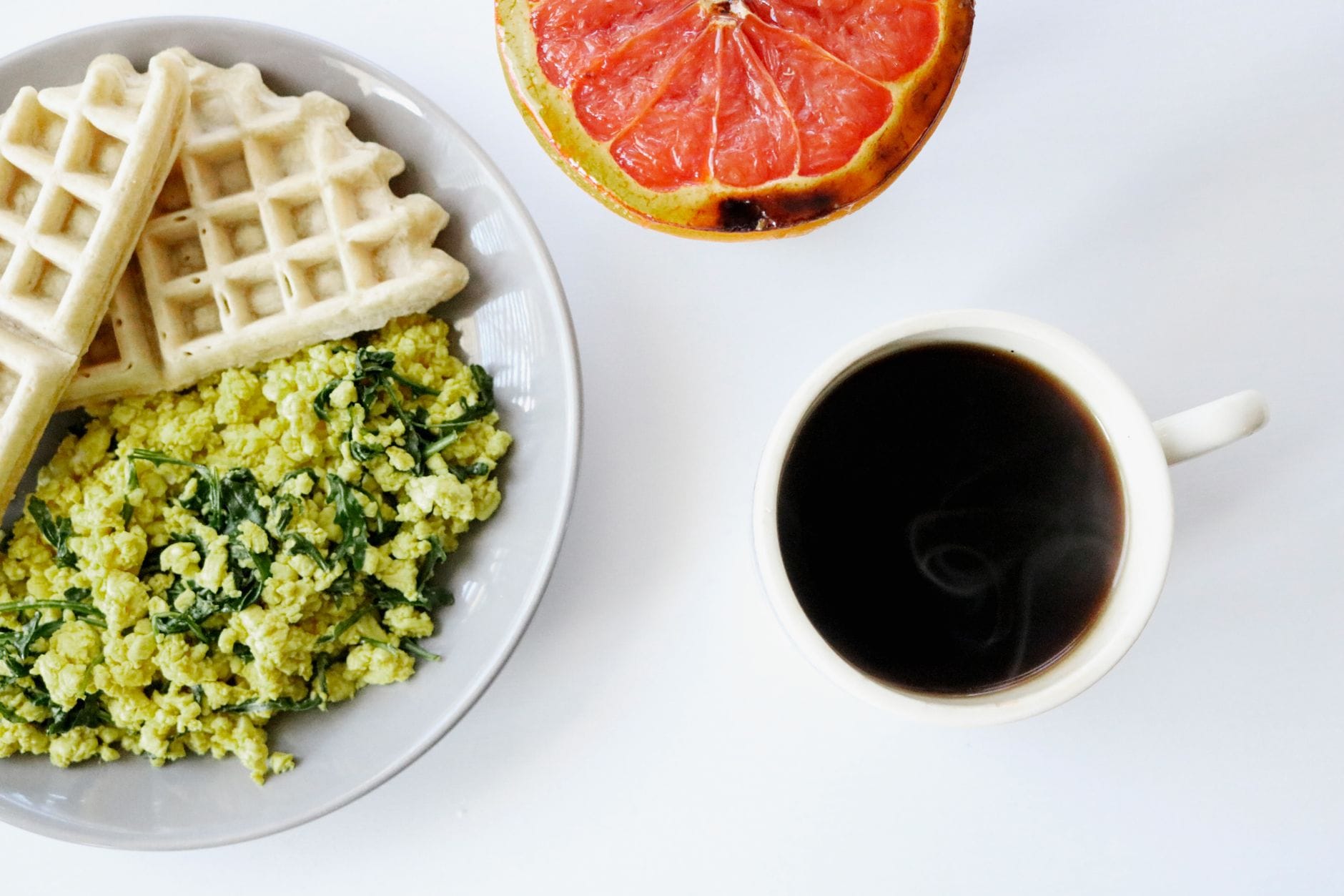 Breakfast plate of waffles, egg scramble, grapefruit half, and coffee