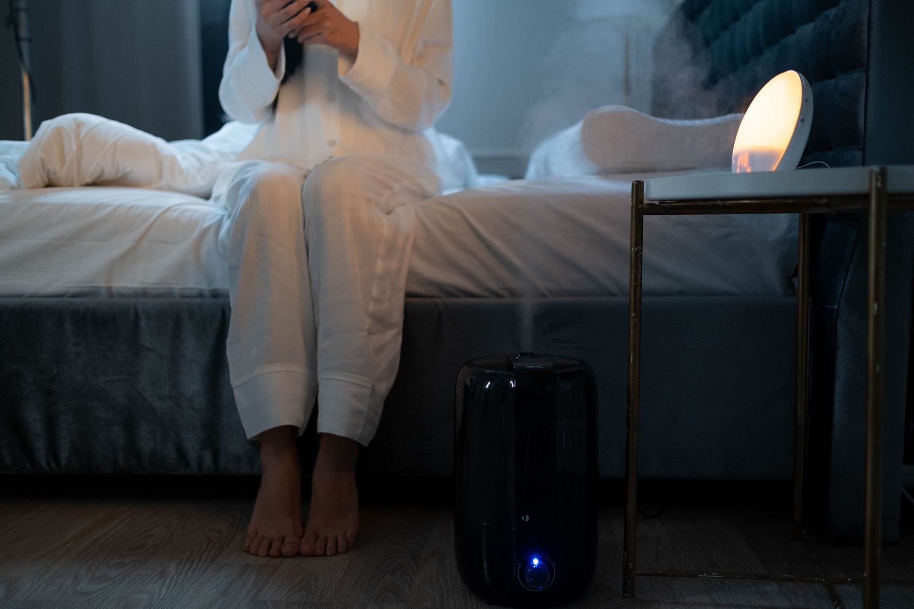Humidifier releasing mist beside a bed at night