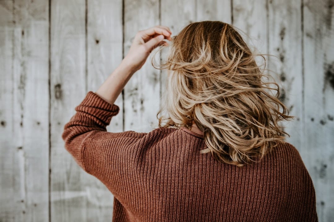 Woman seen from behind running her fingers through wavy hair