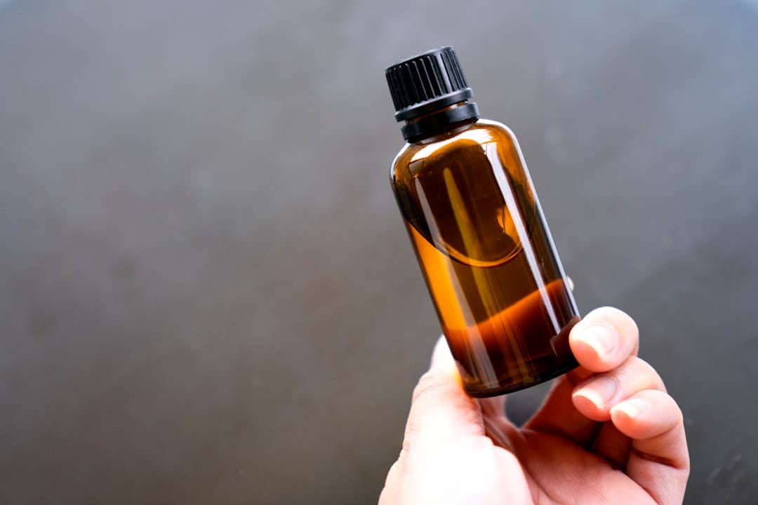 Hand holding up a small amber essential oil bottle