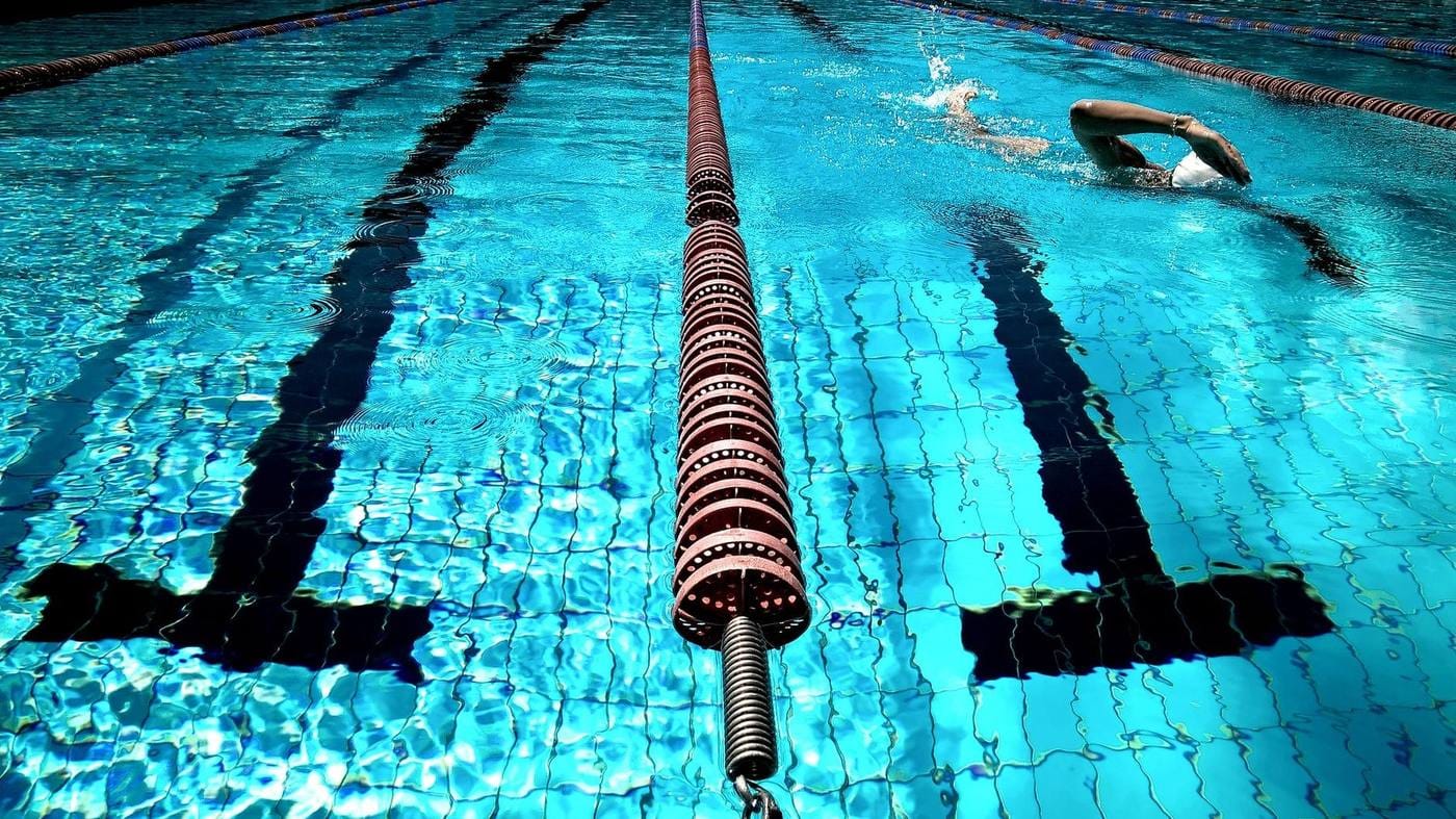 Swimmer doing freestyle laps beside a red lane divider