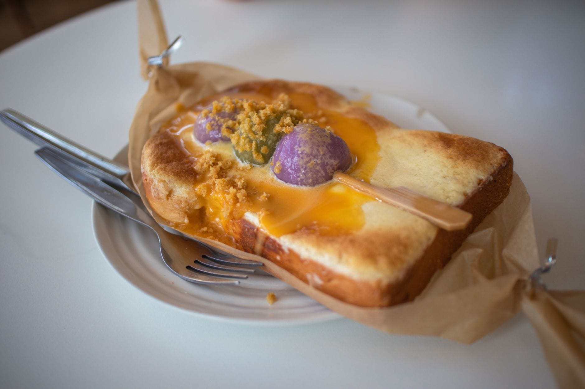 Thick slice of toast with custard, purple ube balls and crumble on parchment