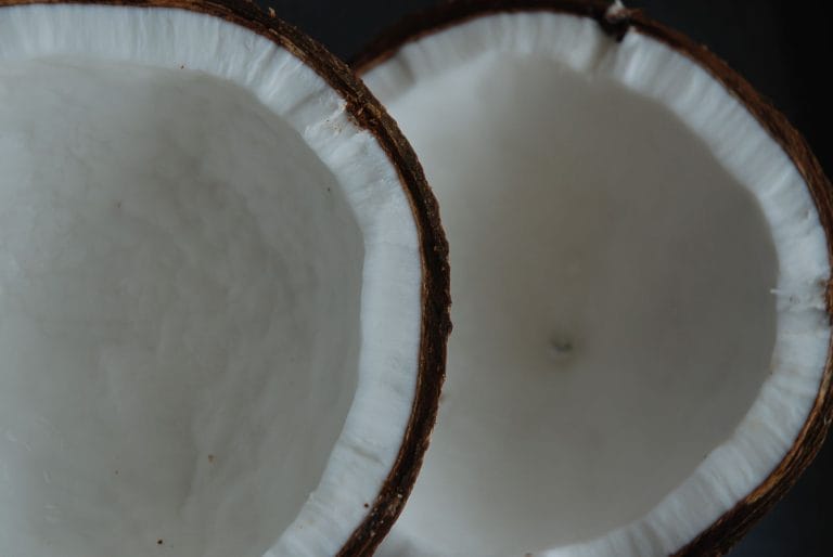 Close-up of two halved coconuts showing thick white flesh inside brown shells