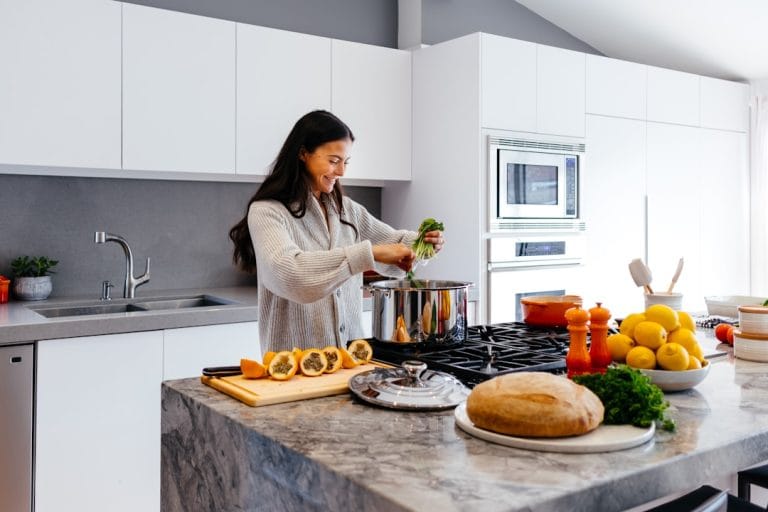 Woman slicing vegetables at a bright kitchen counter with fresh produce