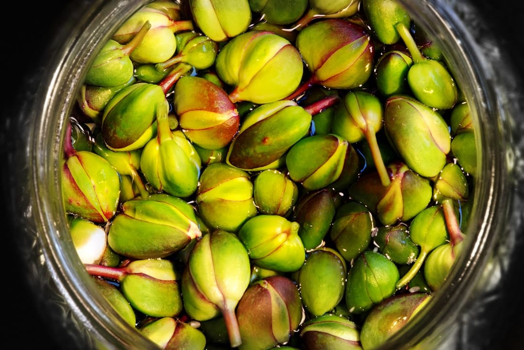 Fresh green caper buds packed tightly in a glass jar