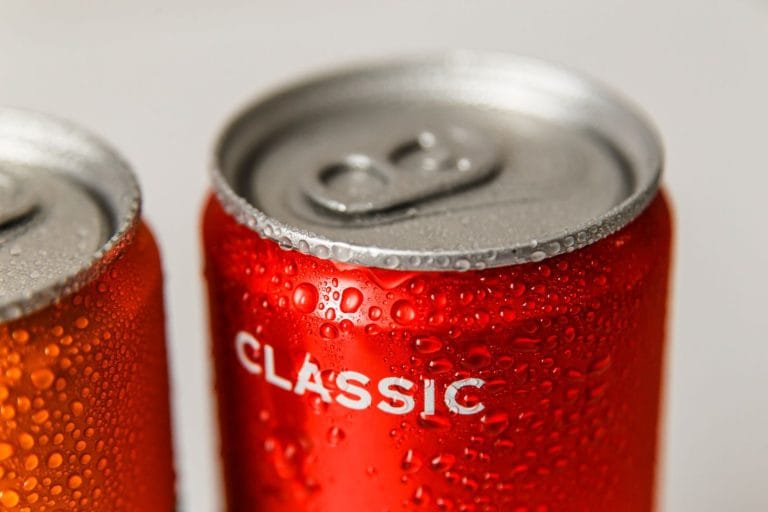 Two chilled drink cans covered in condensation, the front one red and marked only CLASSIC