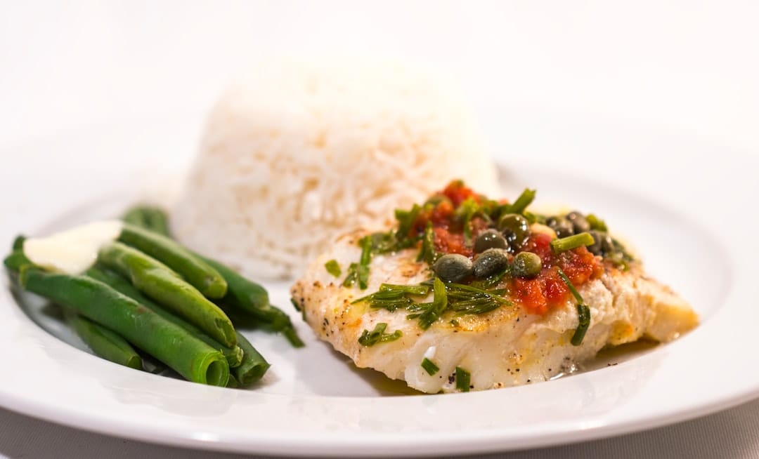 Pan-fried cod topped with capers, tomato and chives, served with green beans and rice
