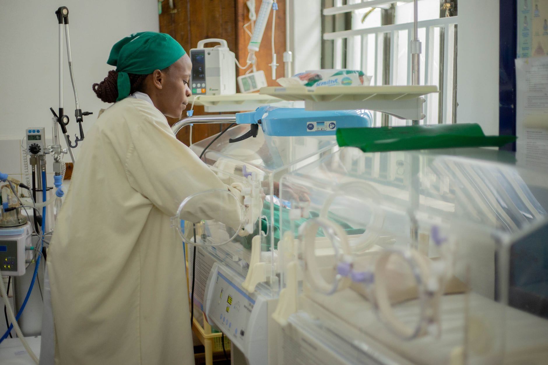 Health worker tending to a newborn in an incubator in a neonatal unit