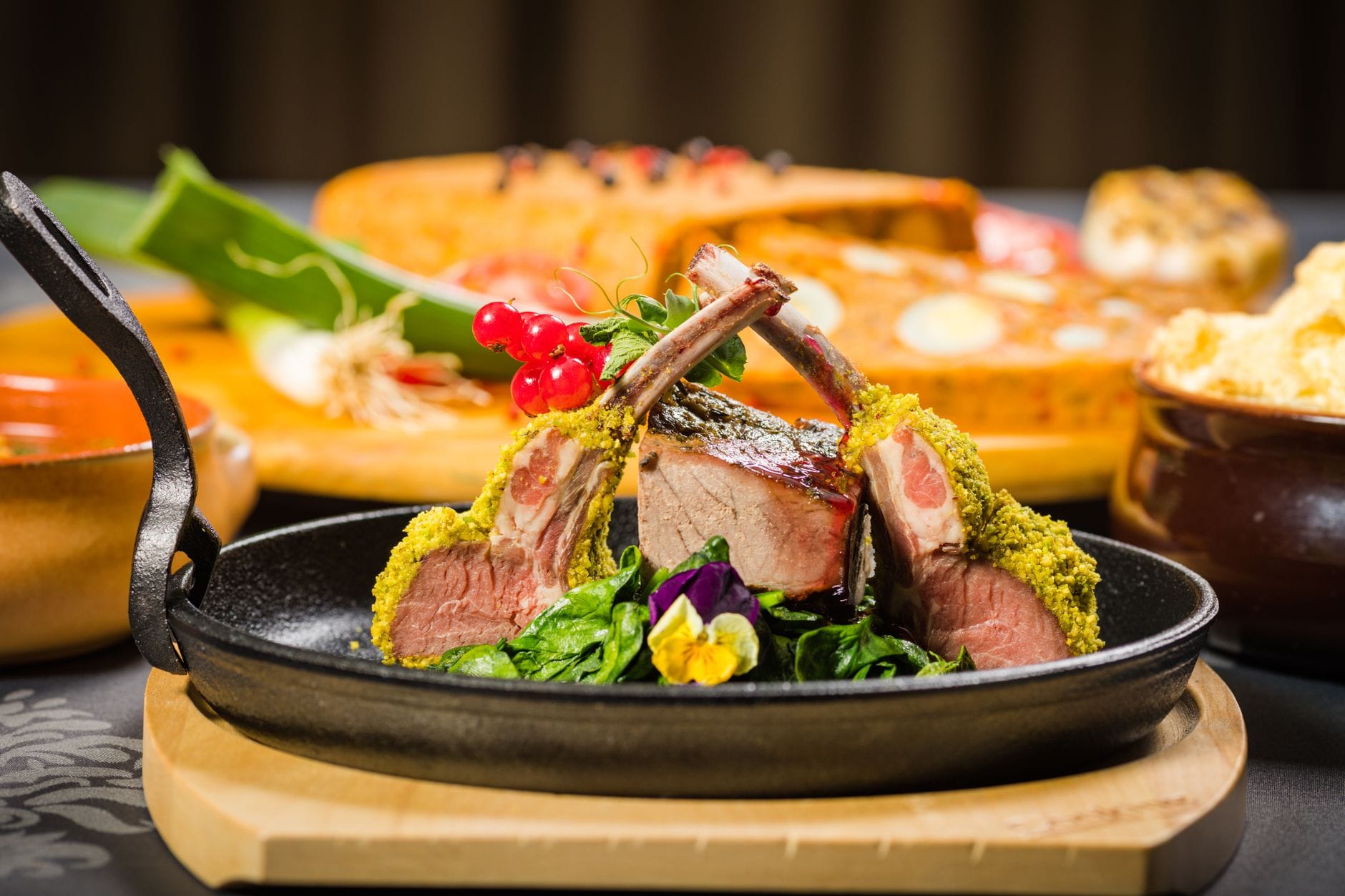 Herb-crusted rack of lamb with frenched bones, sliced pink, in a skillet