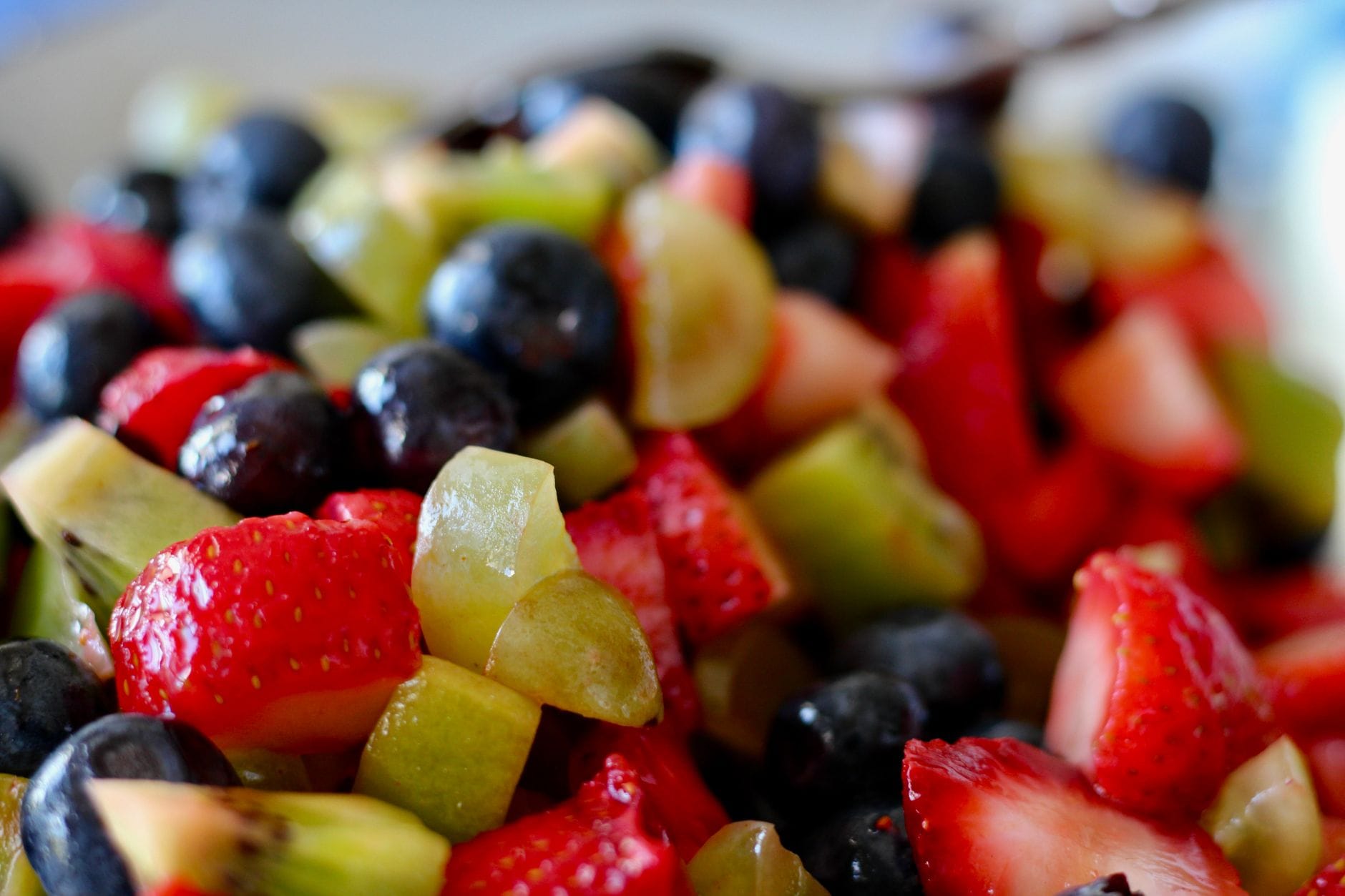 Close-up of strawberries, blueberries, green grapes and kiwi in a fruit salad