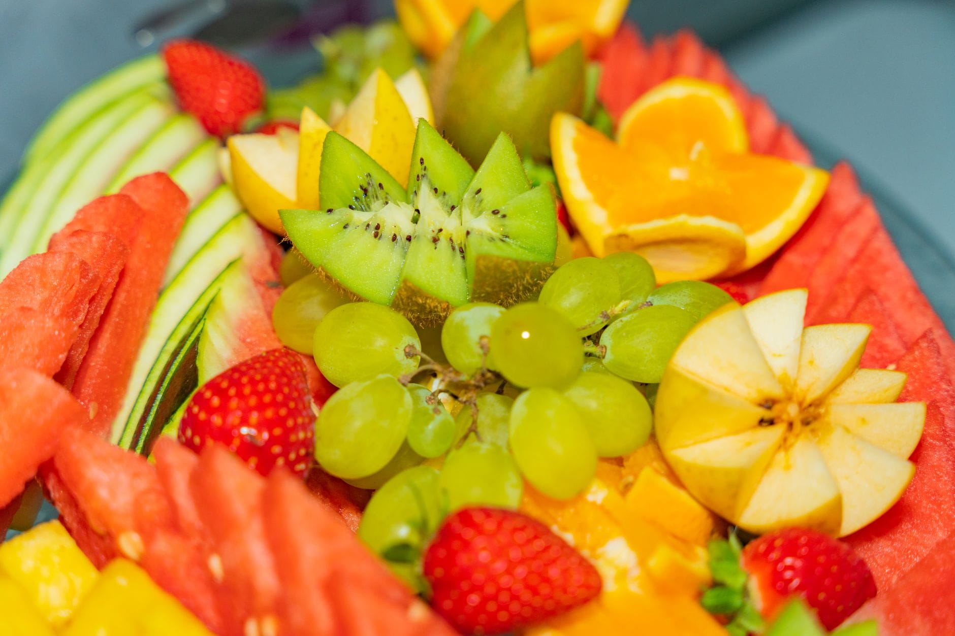 Platter of watermelon, kiwi, grapes, strawberries, orange, apple and mango
