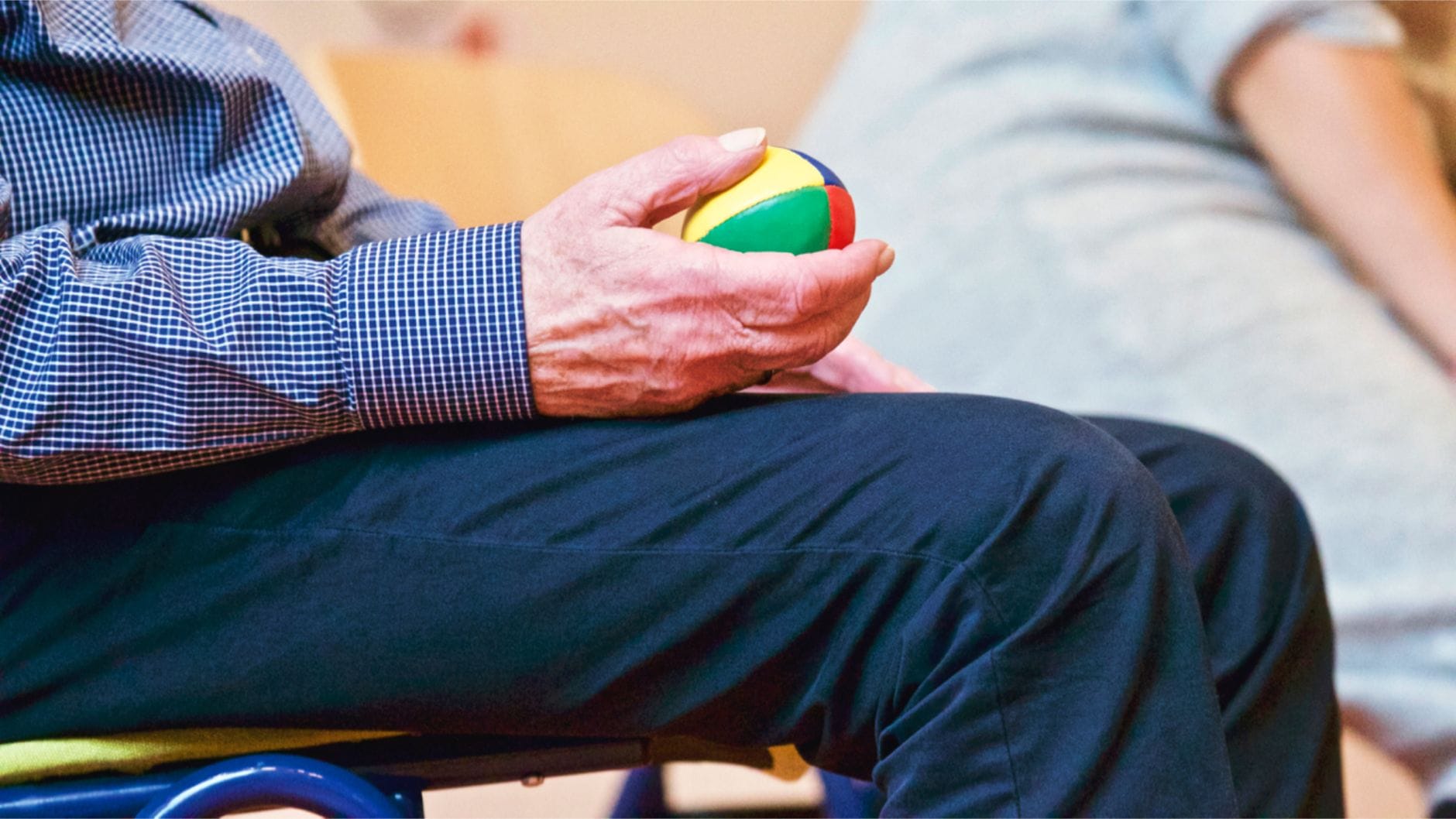 Older adult squeezing a soft multicoloured ball in one hand
