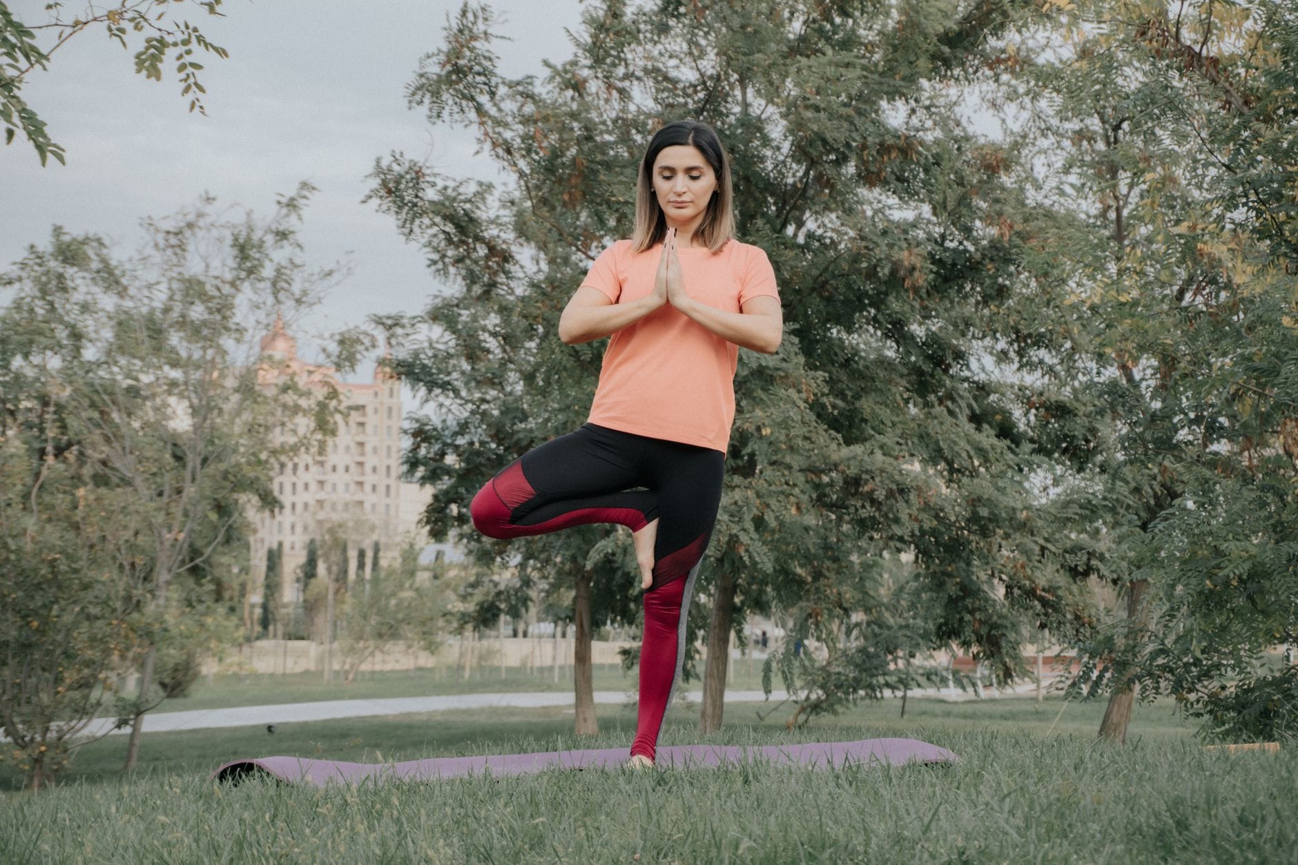 Woman holding yoga tree pose with foot on inner thigh outdoors
