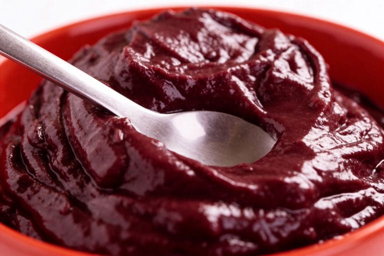 Spoon resting in a bowl of thick, completely smooth deep-red puree