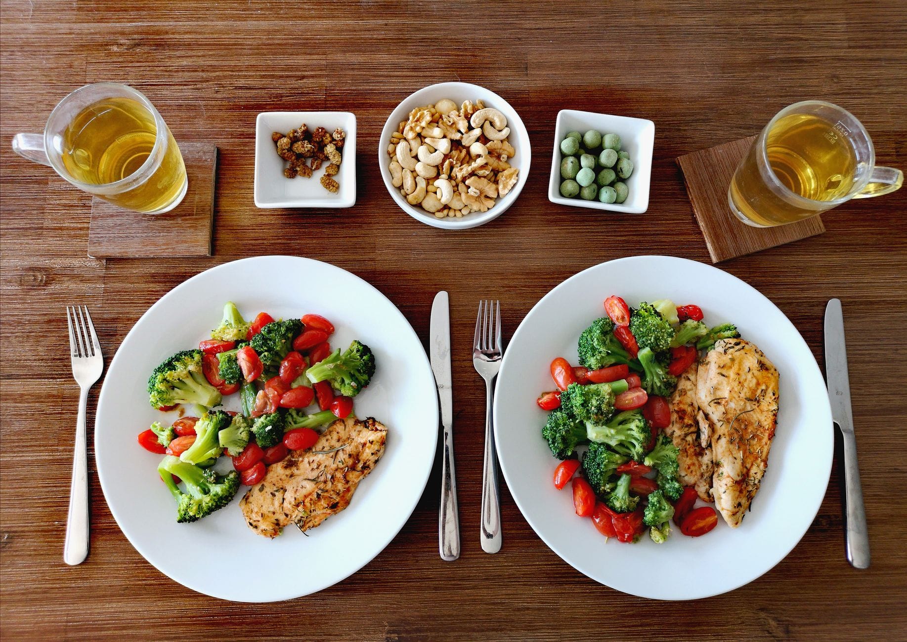 Two plates of grilled chicken breast with broccoli and cherry tomatoes