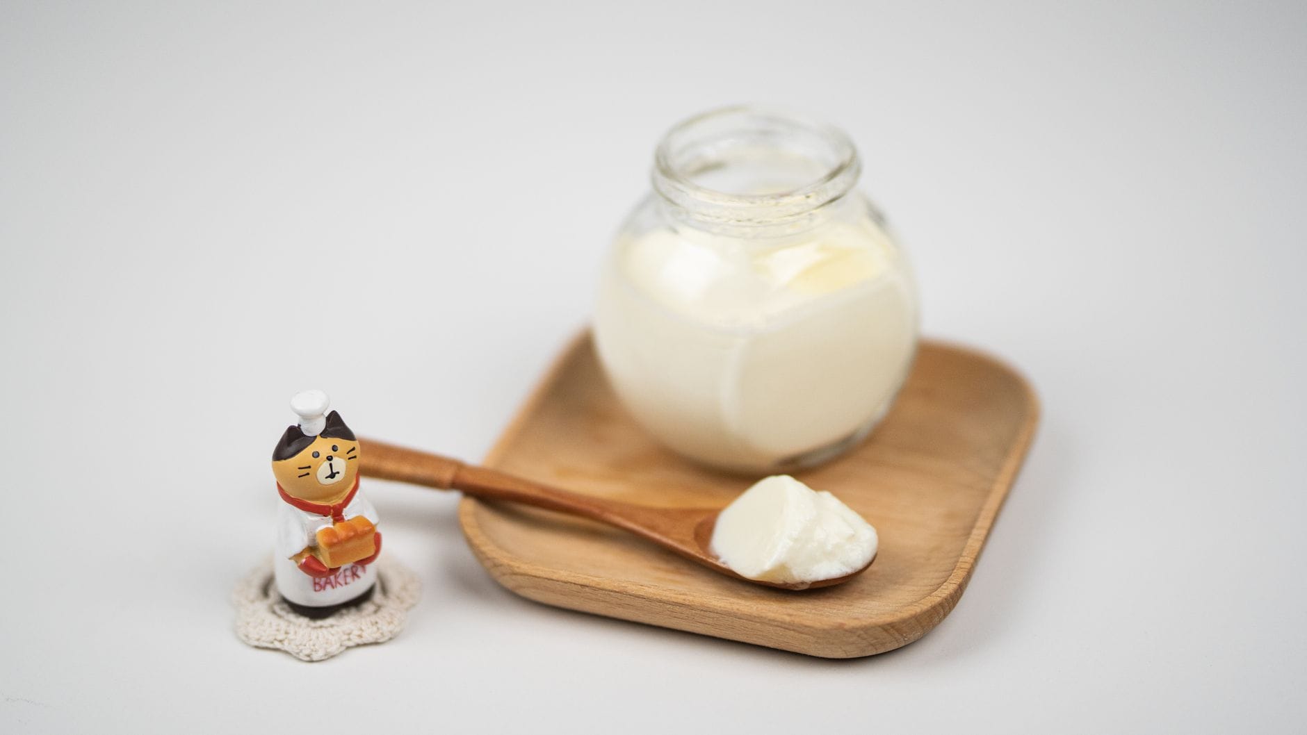 Glass jar of thick cultured cream with a wooden spoon holding a dollop
