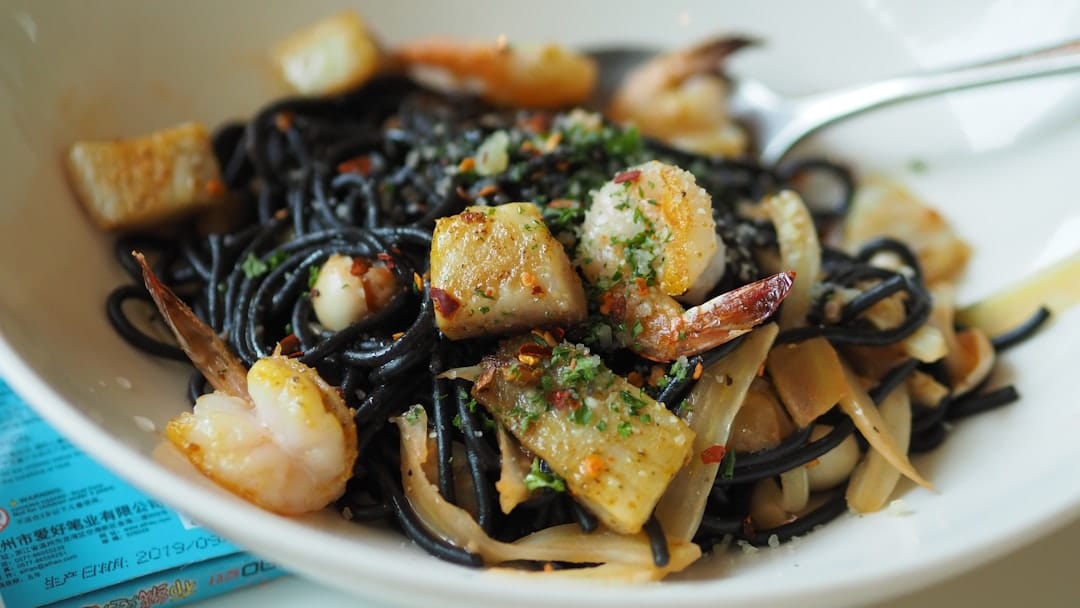 Bowl of black squid ink spaghetti with prawns and seafood pieces