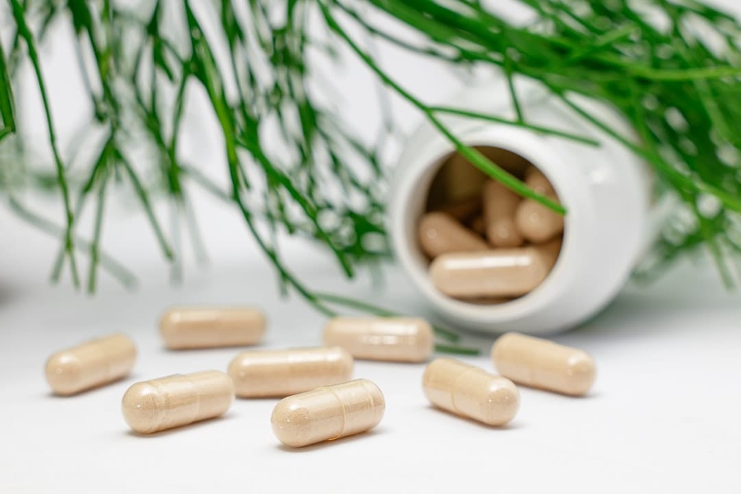 Amber herbal supplement capsules spilling from a small bottle