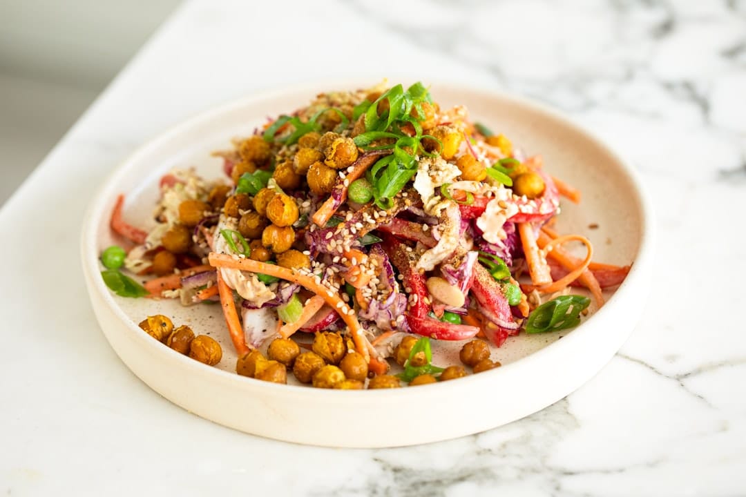 Vegetarian bowl of roasted chickpeas, shredded carrot, cabbage and sesame seeds