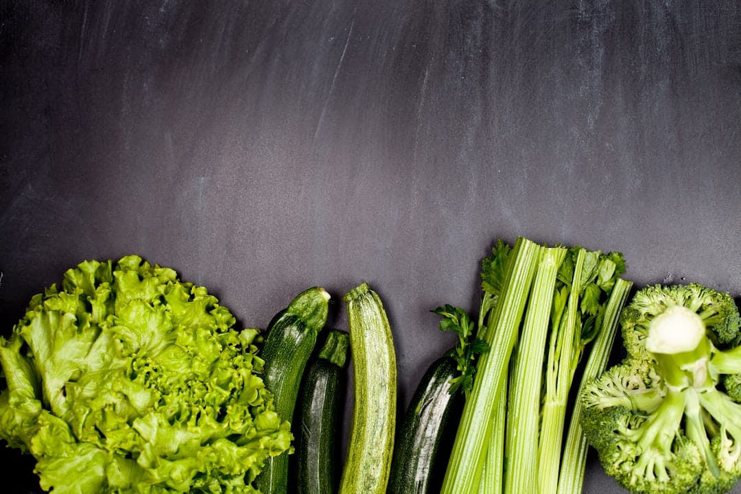 Flat lay of leafy lettuce, celery, courgette and broccoli on slate