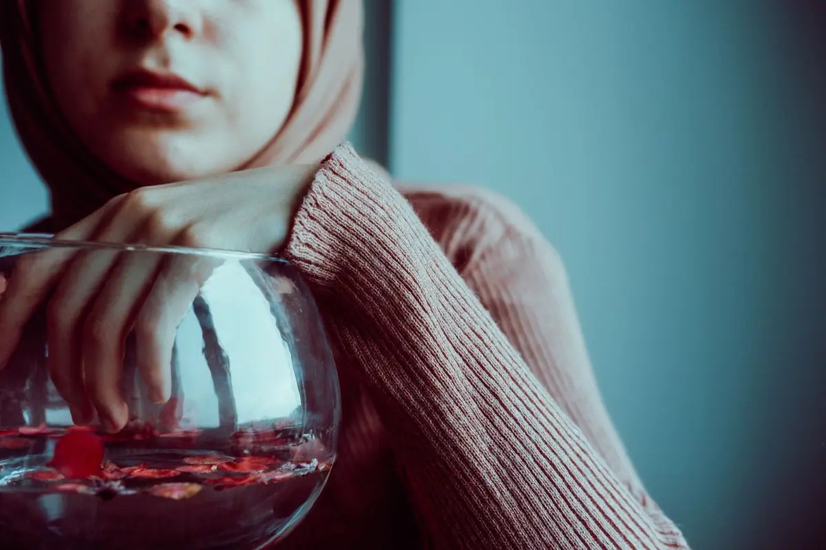 Two hands resting in a bowl of warm water on a wooden surface