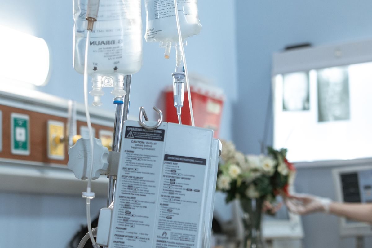 Intravenous fluid bags hanging from a stand with an infusion pump in a hospital room