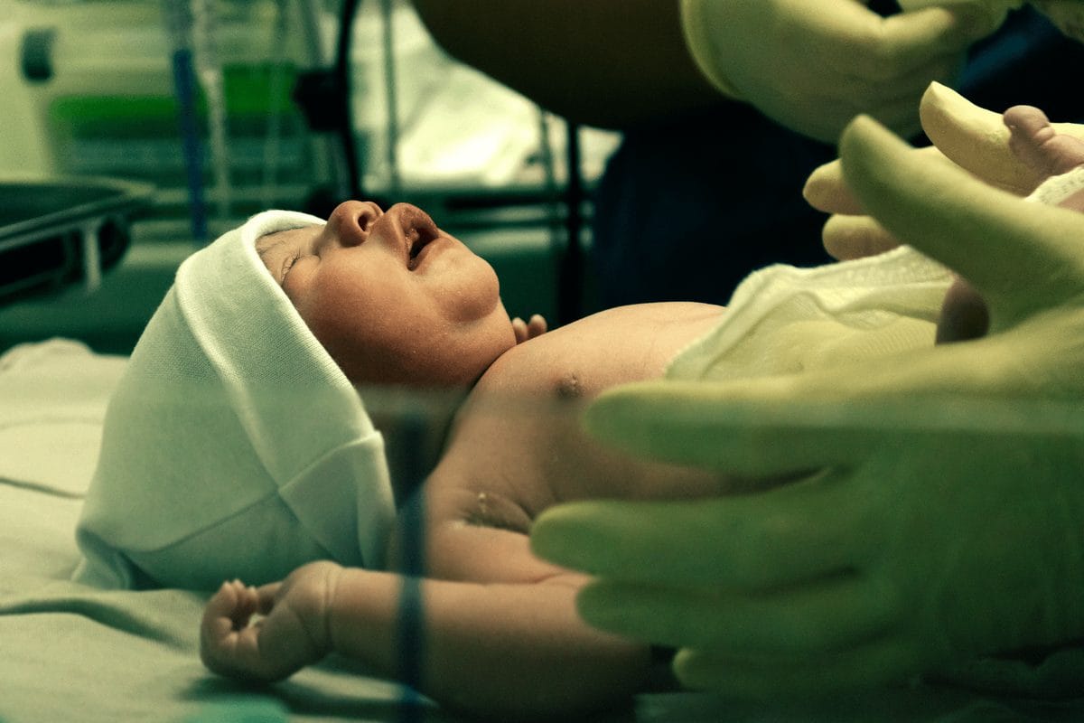 Nurse in gloves gently holding a newborn baby in a hospital